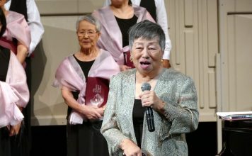 声楽家でさくらシンガーズの音楽監督・理事長のルース鈴木さん、死去 2018年の定期演奏会で挨拶するルース鈴木さん。後方左手は結成当初からのメンバーの高橋美奈子さん。Photo by Louise Akuzawa © the Vancouver Shinpo