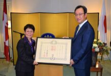 津田佐江子氏の旭日小綬章、叙勲伝達式、なごやかに 津田氏(左)と羽鳥総領事。勲記授与のあと記念撮影。Photo by © the Vancouver Shinpo