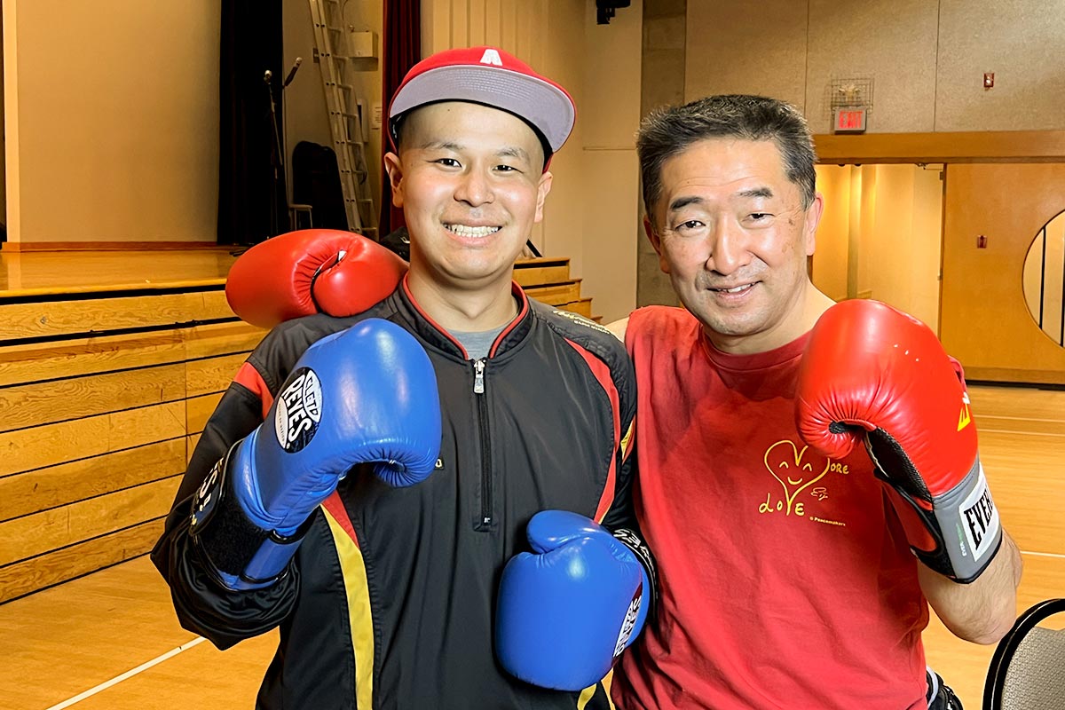 ボクシングでハリーさんを応援する吉川英治さん（右）と笑顔でファイティングポーズの米澤幸也（ハリー）さん（左）。2023年1月22日、日系文化センター・博物館。Photo by ©Koichi Saito