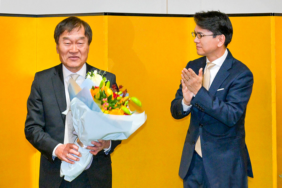 花束を受け取り笑顔を見せる長井明氏（左）と、拍手で祝福する丸山浩平総領事。2023年2月28日、在バンクーバー日本国総領事公邸。Photo by Koichi Saito/Japan Canada Today