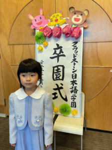 卒園式の看板前で。写真提供：グラッドストーン日本語学園