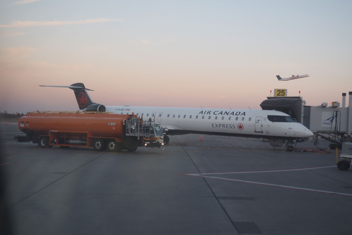 エア・カナダの旧ボンバルディアCRJ。離陸中なのはポーター航空の旧ボンバルディアQシリーズのプロペラ機(23年10月3日、オンタリオ州で大塚圭一郎撮影)