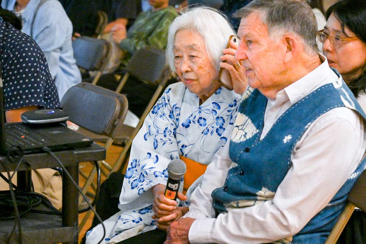 電話でハミルトンのサーロー節子さんと言葉を交わす、ランメル幸さんと夫のチャールズさん。2025年7月5日、バンクーバー市。Photo by Koichi Saito