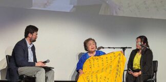 サーロー節子さんインタビュー「I have to break the silence」プライバシーを犠牲にして訴え続けたトロントでの活動 講演の時にはいつも持っているという被爆時に広島女学院に通っていた学生や教職員の名前が書かれた黄色い布を広げて説明するサーロー節子さん。2025年7月5日、ハミルトン市。撮影 三島直美/日加トゥデイ