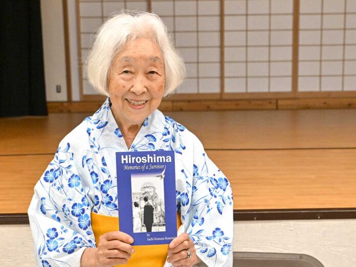 著書「Hiroshima-Memories of a Survivor」を持ち笑顔を見せるランメル幸さん。2025年7月5日、バンクーバー市。Photo by Koichi Saito