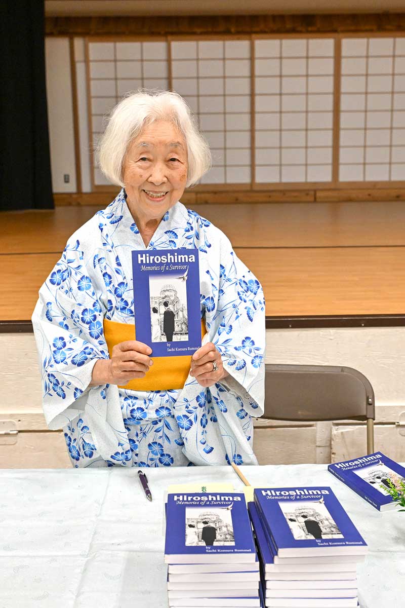 著書「Hiroshima-Memories of a Survivor」を持ち笑顔を見せるランメル幸さん。2025年7月5日、バンクーバー市。Photo by Koichi Saito
