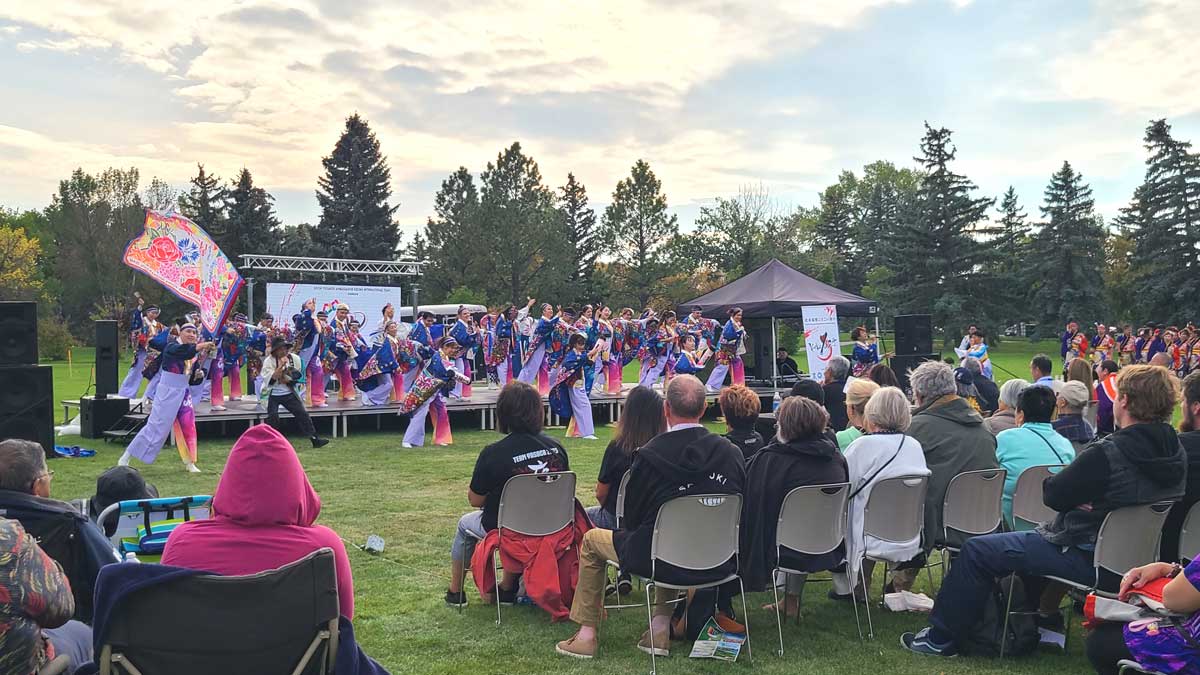 秋空の下、色鮮やかな衣装をまとった踊り子たちが舞台に立つ。芝生に座る観客も手拍子で応え、会場が一体となった。2025年9月27日、アルバータ州レスブリッジ市。提供:北米国際よさこい祭り参加者