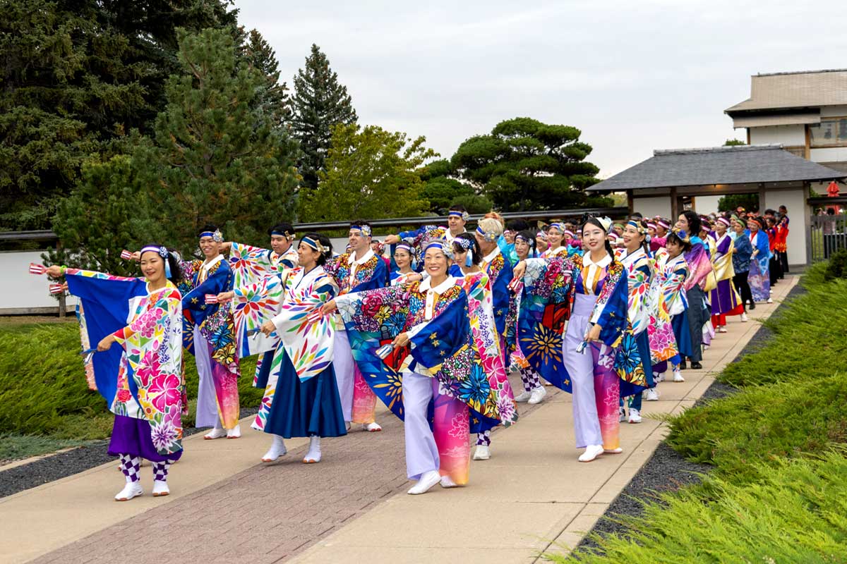 色鮮やかな衣装をまとった踊り子たちが、日加友好日本庭園の小道を進む。鳴子の音が響き、祭りの幕開けを告げた。2025年9月27日、アルバータ州レスブリッジ市。提供:北米国際よさこい祭り参加者