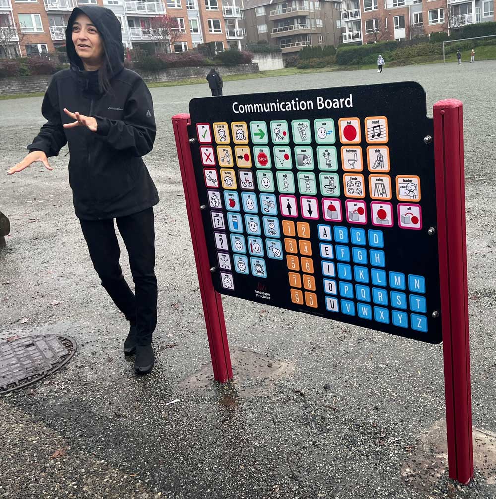 ノースバンクーバー学区の小学校の校庭にはコミュニケーションボードという、絵文字&アルファベット板が立つと説明してくれるノースバンクーバー学区教育委員会委員のカルビアマンさん。2025年11月21日。撮影 AK Jump Educational Consulting Inc.