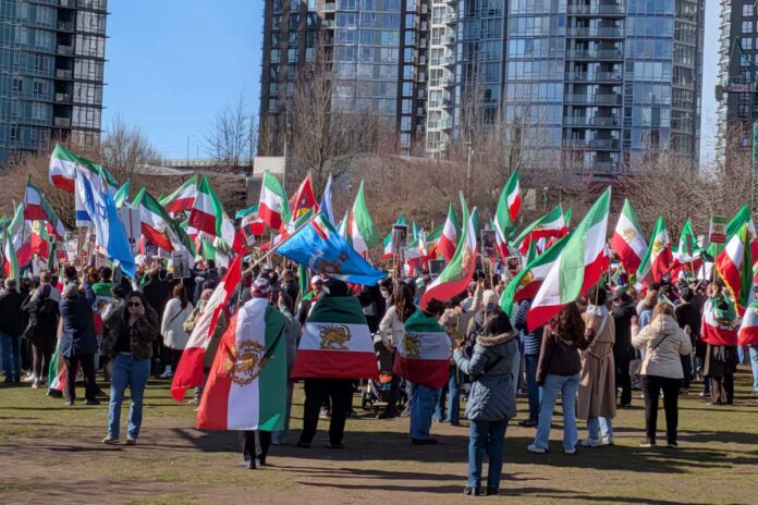 1_Iranian-demo-Vancouver_2026-3-1 バンクーバー市デイビッド・ラム公園に集まったイラン系カナダ人コミュニティの人たち。太陽と剣を持つ獅子の紋章が中央に描かれた国旗が多く見られた。2026年3月1日、バンクーバー市。撮影 日加トゥデイ