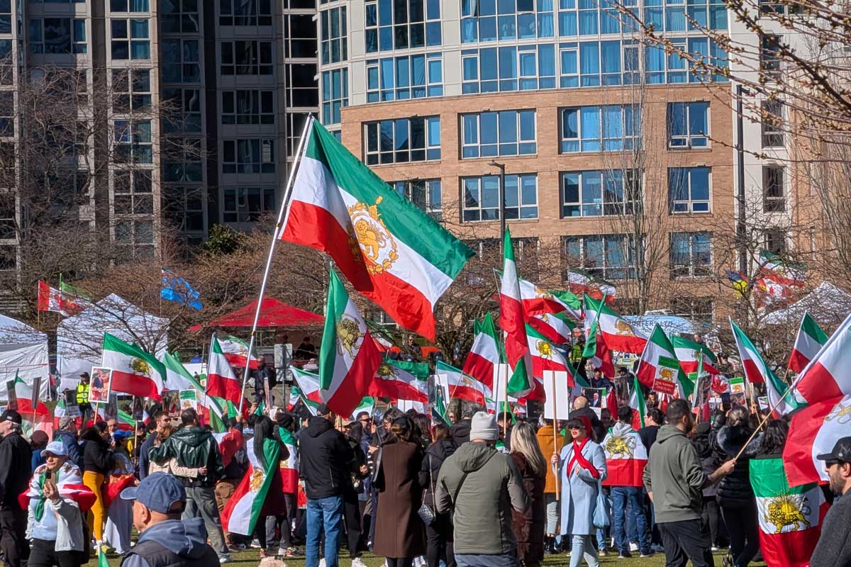 バンクーバー市デイビッド・ラム公園に集まったイラン系カナダ人コミュニティの人たち。太陽と剣を持つ獅子の紋章が中央に描かれた国旗が多く見られた。2026年3月1日、バンクーバー市。撮影　日加トゥデイ