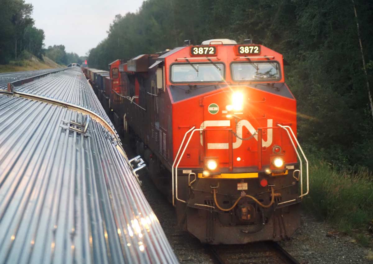 ＶＩＡ鉄道カナダのカナディアンとすれ違うカナディアン・ナショナル鉄道（ＣＮ）の貨物列車（２０２４年８月、大塚圭一郎撮影）