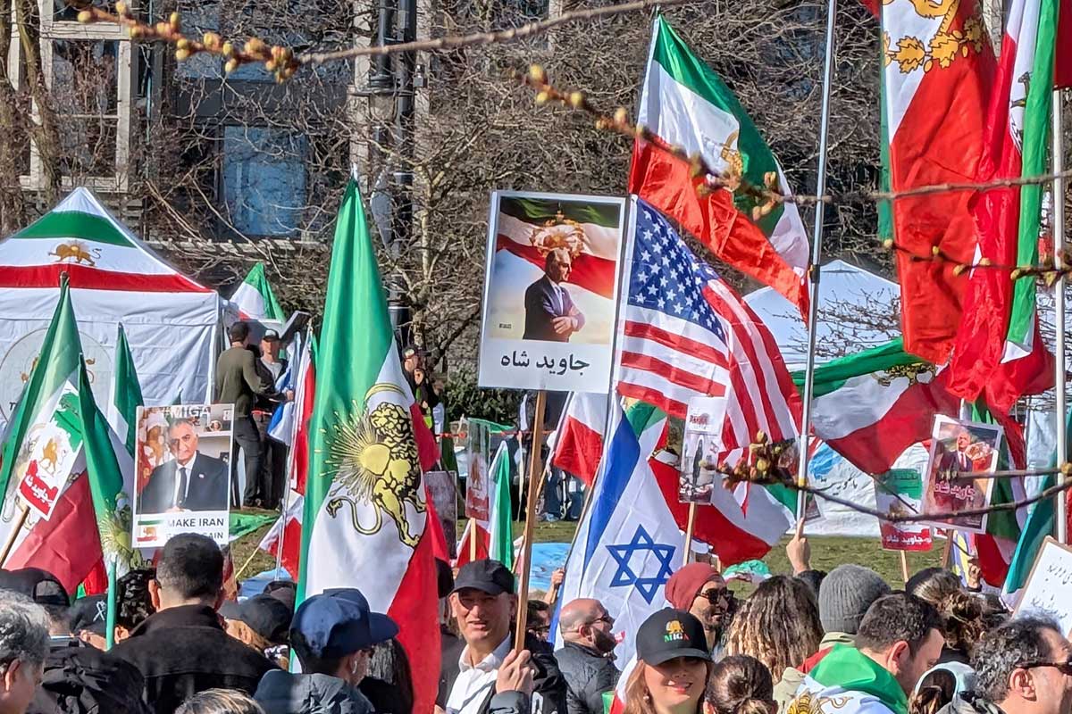 太陽と剣を持つ獅子の紋章が中央に描かれた国旗と共にアメリカやイスラエルの国旗も。2026年3月1日、バンクーバー市。撮影　日加トゥデイ