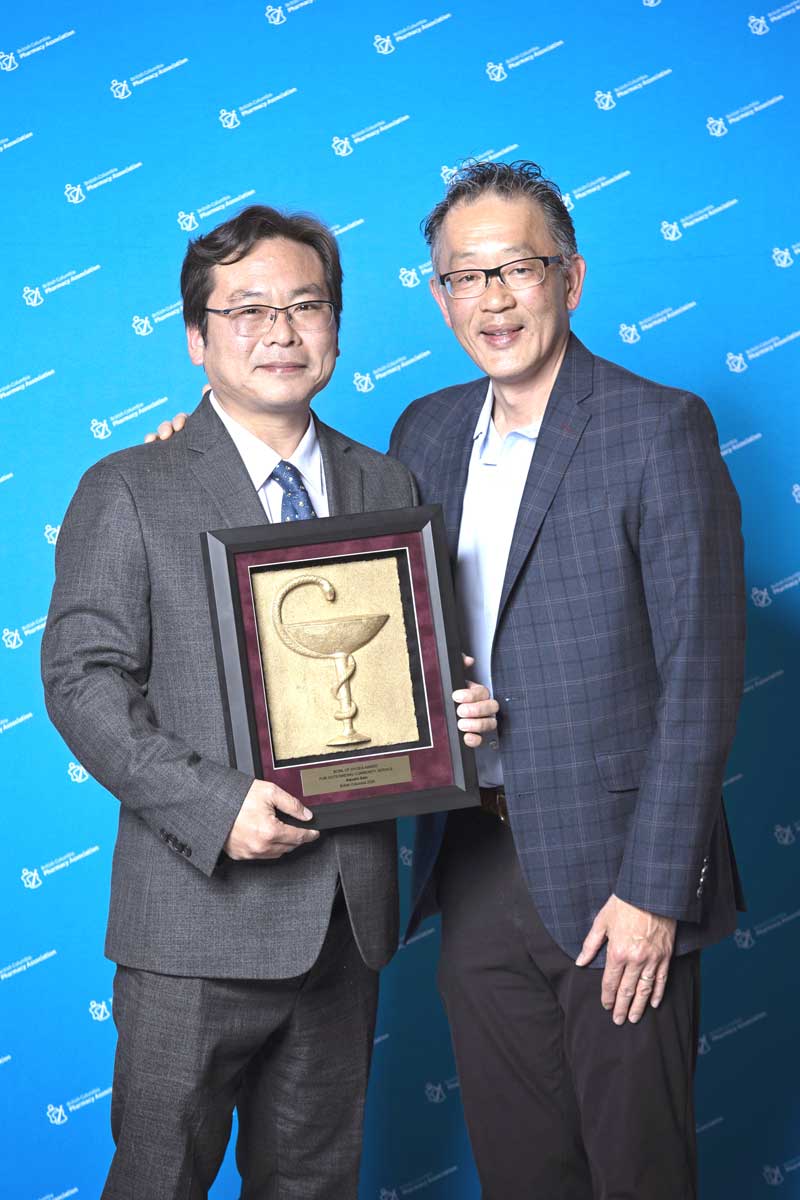 2026年5月2日、バンクーバー市で行われた授賞式で。佐藤厚さん（左）と賞のプレゼンターを務めたロンドンドラッグス薬局部門GMのChris Chiewさんと一緒に。Photo courtesy of The BC Pharmacy Association