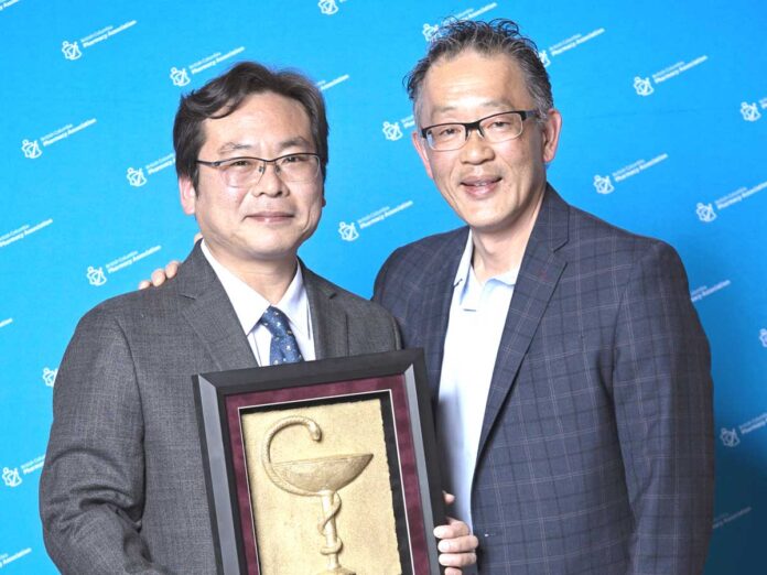 2026年5月2日、バンクーバー市で行われた授賞式で。佐藤厚さん（左）と賞のプレゼンターを務めたロンドンドラッグス薬局部門GMのChris Chiewさんと一緒に。Photo courtesy of The BC Pharmacy Association