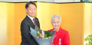 メアリー・キタガワさん旭日単光章受章、日系カナダ人の誇りを胸に 旭日単光章を胸に、両手に余るほどの大きな花束を髙橋総領事とともに持つ、キタガワさん。2026年5月22日、バンクーバー市。写真 斉藤光一/日加トゥデイ