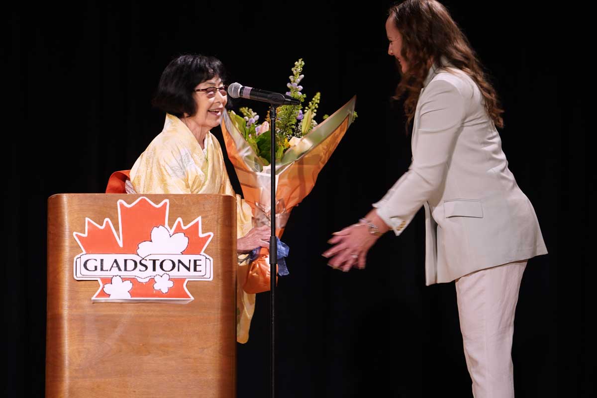 卒業生を代表してバンクス安里子さんから村上陽子学園長に花束を贈る。2026年5月30日、日系文化センターホール。写真提供　グラッドストーン日本語学園